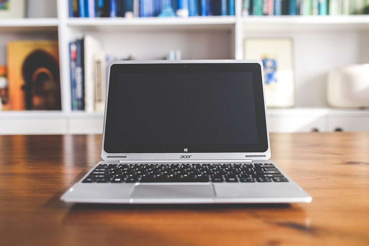 Laptop dan buku catatan di meja; foto ilustrasi.